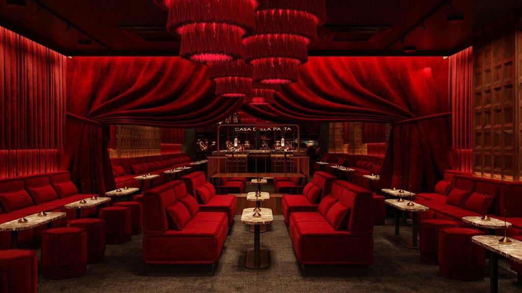 Velvet booths beneath red fringe chandeliers